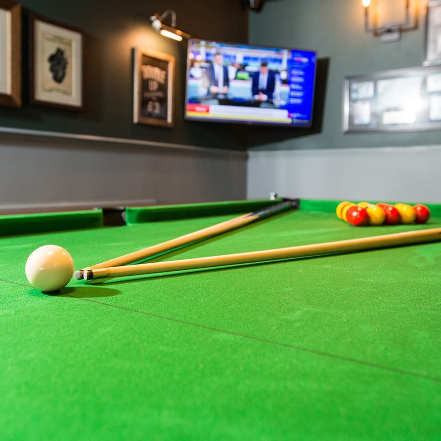 pool table with tv showing sports results in the background